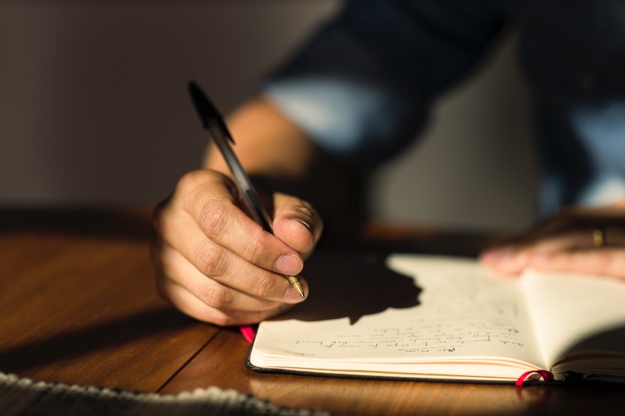 man writing in a journal