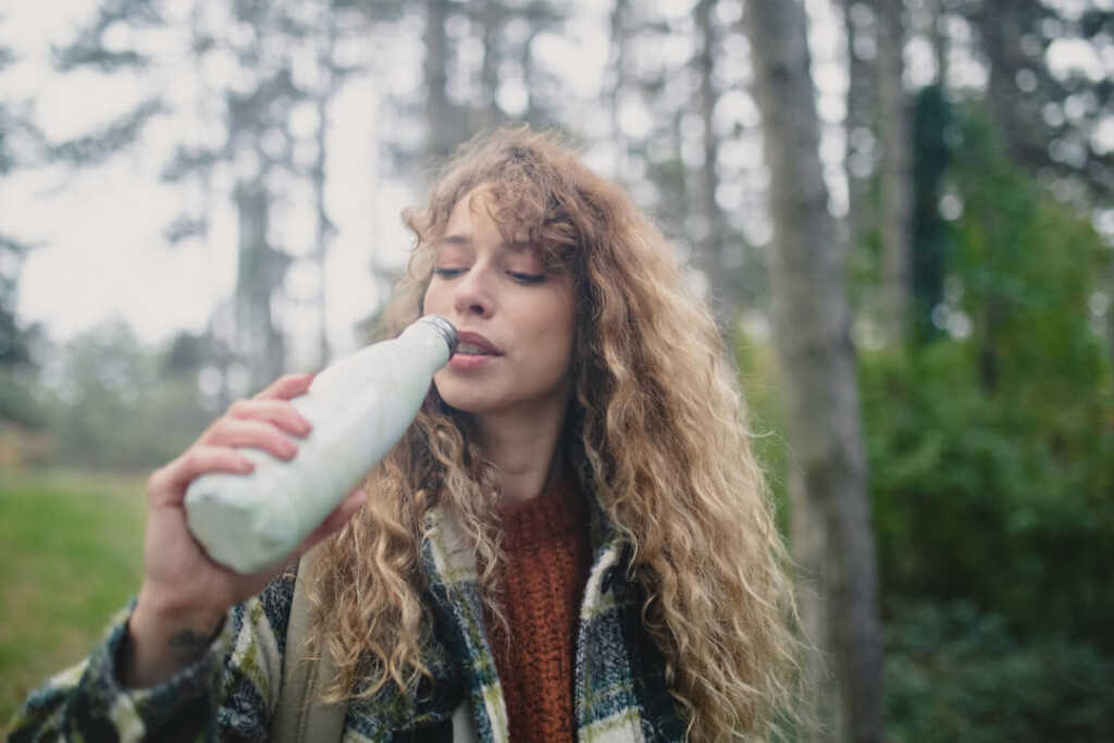 outdoor enthusiast drinking from branded water bottle