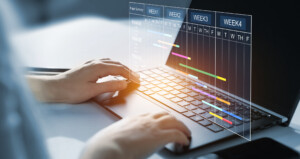 Project manager working on laptop and updating tasks and milestones progress planning with Gantt chart scheduling interface for company on virtual screen. Business Project Management System